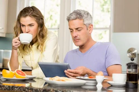 Happy couple using tablet and having breakfast Stock-Fotos