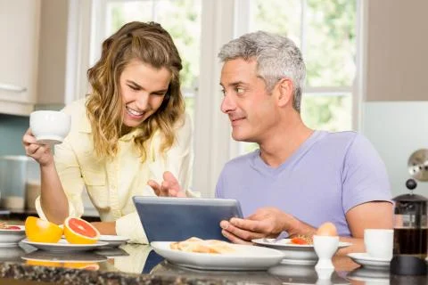 Happy couple using tablet and having breakfast Stock-Fotos