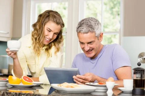 Happy couple using tablet and having breakfast Stock-Fotos
