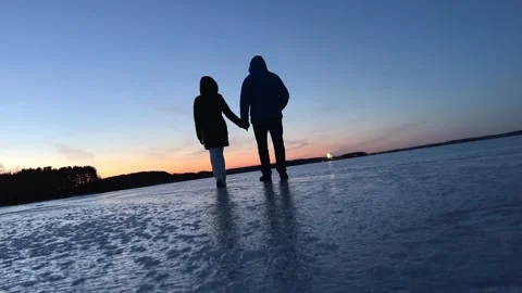 Happy couple walk on the icy surface against the background of the sunset Stock Footage 270443732