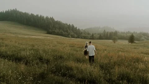 Happy couple walking through the mountain flowers field. Family hiking in the Stock Footage 271028321