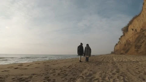 Happy couple walking on the wild beach on cloudy sunrise or sunset Stock Footage 167874772