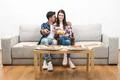 The happy couple watching tv with a pizza and a beer on the white background Photo