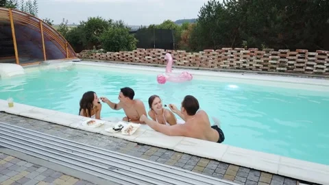 Happy couples eating sushi into a pool. Men feeding women with sushi in pool Stock Footage 149606348