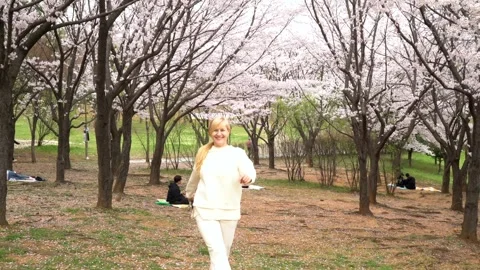 Happy couples relax under blooming cherry blossom trees, enjoying peaceful Video stock 305993949
