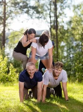 Happy Coworkers Making Human Pyramid On Grassy Field 写真素材