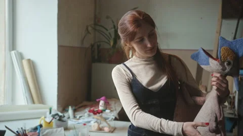 Happy crafted showing handmade wool dinosaur in workshop Stock Footage 219762852