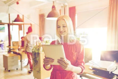 Happy creative female office worker with tablet pc Stock Photos