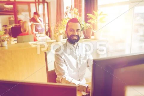 Happy creative male office worker with computer Stock Photos