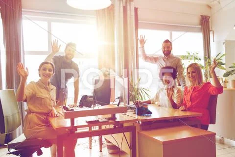 Happy creative team waving hands in office Stock Photos