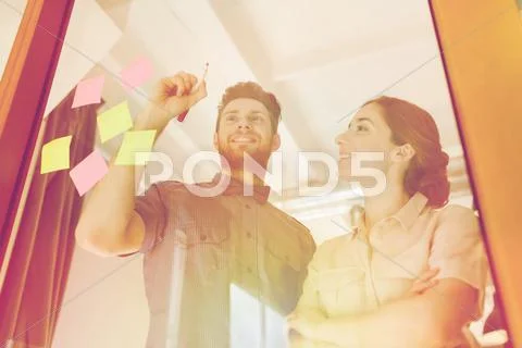 Happy creative team writing on blank office glass Stock Photos