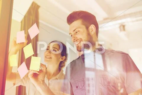 Happy creative team writing on stickers at office Stock Photos