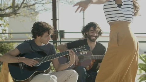 Happy curly-haired men playing guitar at rooftop party Stock Footage 166840690