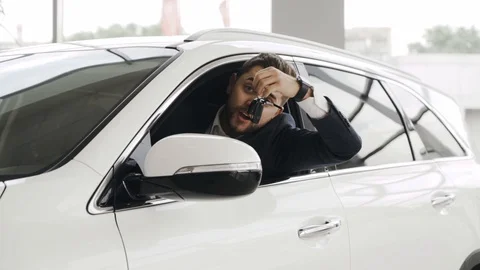 Happy customer is getting out of the car window at the car salon, with the keys Stock Footage 94344744