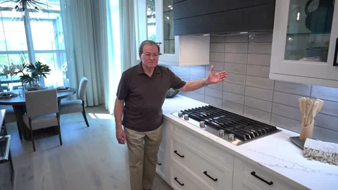 Happy customer in the kitchen shows off the tile backsplash on his new home Stock Footage 284198601