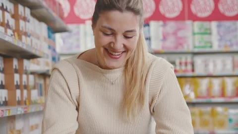 Happy customer using a smartphone at the grocery store Stock Footage 297850080