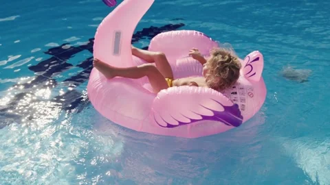 Happy cute boy is sitting on inflatable flamingo with mother in swimming pool Stock Footage 244467292