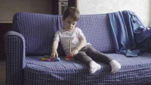 Happy cute boy spending time together at home, sitting on sofa and playing Stock Footage 189874469