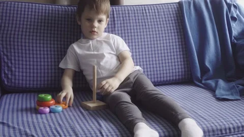 Happy cute boy spending time together at home, sitting on sofa and playing Stock Footage 189875279