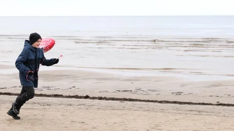 Happy cute boy standing with red ballon heart Stock Footage 145977154