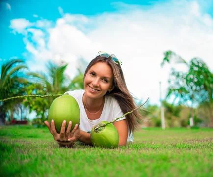 Happy cute model lying outside on the grass with coconut. Sunny summer vacation Stock Photos
