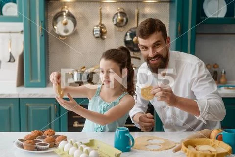 Happy dad with his daughter cut out smile cookies in the kitchen Stock Photos