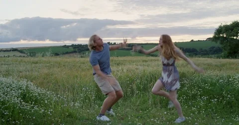 Happy dancer couple dancing silly freestyle dance in open green field enjoying Stock Footage