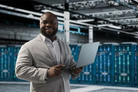 Happy data center engineer using laptop to debug software issues Stock Photos