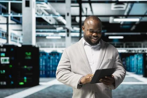 Happy data center engineer writing lines of code running on tablet 스톡 사진