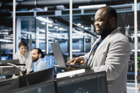 Happy data center facility admin using laptop to update supercomputers software 스톡 사진