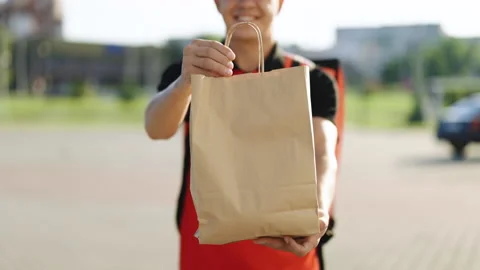Happy delivery worker holding packet with food looking at the camera and smiling Stock Footage 194599609