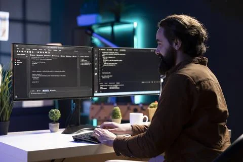 Happy developer in apartment writing lines of binary code on computer Stock Photos