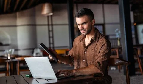 Happy digital nomad programmer working remotely on laptop in a stylish cafe Stock Photos