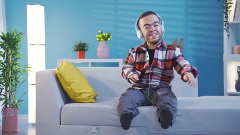 Happy disabled dwarf young man listening music with headphones having fun  動画素材 230972871