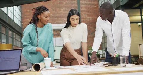 Happy diverse architects looking at architectural blueprints and discussing work Stock Footage 336366251