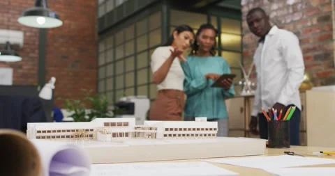 Happy diverse architects looking at architectural models and using tablet at Stock Footage 340968166