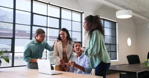 Happy diverse colleagues discussing work around laptop and celebrating in office Stock Footage 317213433