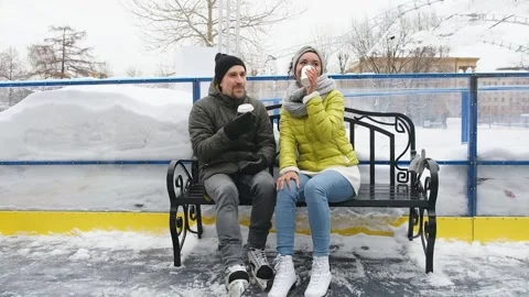 Happy diverse couple drinking coffee before skating on ice rink outdoors Stock Footage 270176519