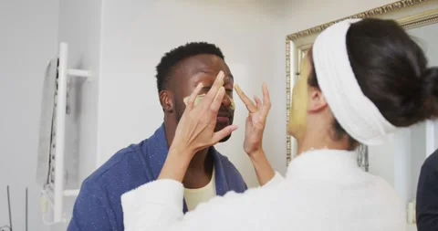 Happy diverse couple looking at each other and doing make up in bathroom Stock Footage 335682199