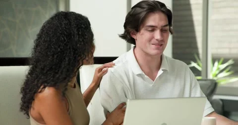 Happy diverse couple sitting at table, using laptop and shredding documents in Stock Footage 317367450