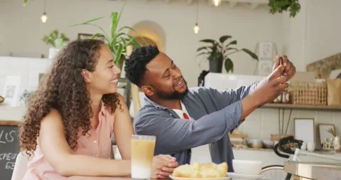 Happy diverse couple spending time together at cafe, drinking coffee and taking Vídeo Stock 344252345