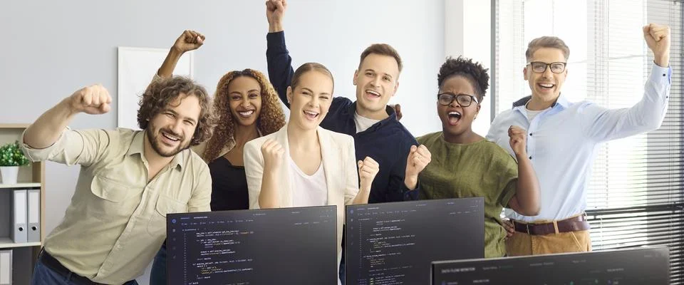 Happy diverse developers team cheering in office after coding project success Stock Photos