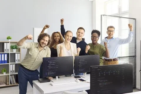 Happy diverse developers team cheering in office after coding project success Stock Photos