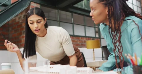 Happy diverse female architects looking at architectural models at office Stock Footage 344330190