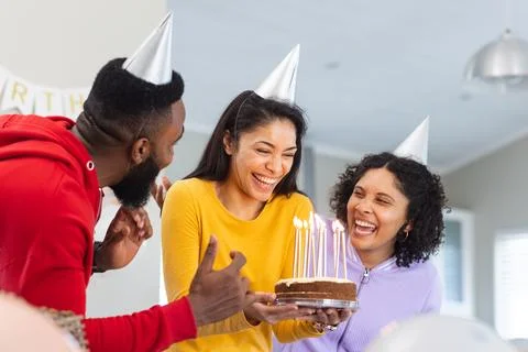 Happy diverse friends celebrating birthday, holding cake with candles Stock Photos