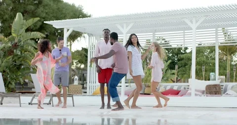 Happy diverse group of friends dancing holding cocktails by swimming pool Stock Footage 340968370