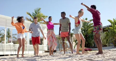 Happy diverse group of friends dancing on beach with beach house and palm trees Stock Footage 340979471