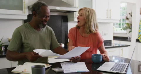 Happy diverse senior couple using laptop computer and paying bills in kitchen Stock Footage 148890071