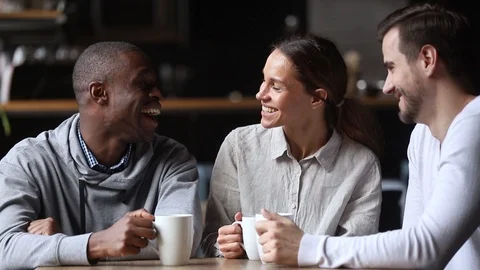 Happy diverse young friends chatting laughing drink tea at meeting Stock Footage