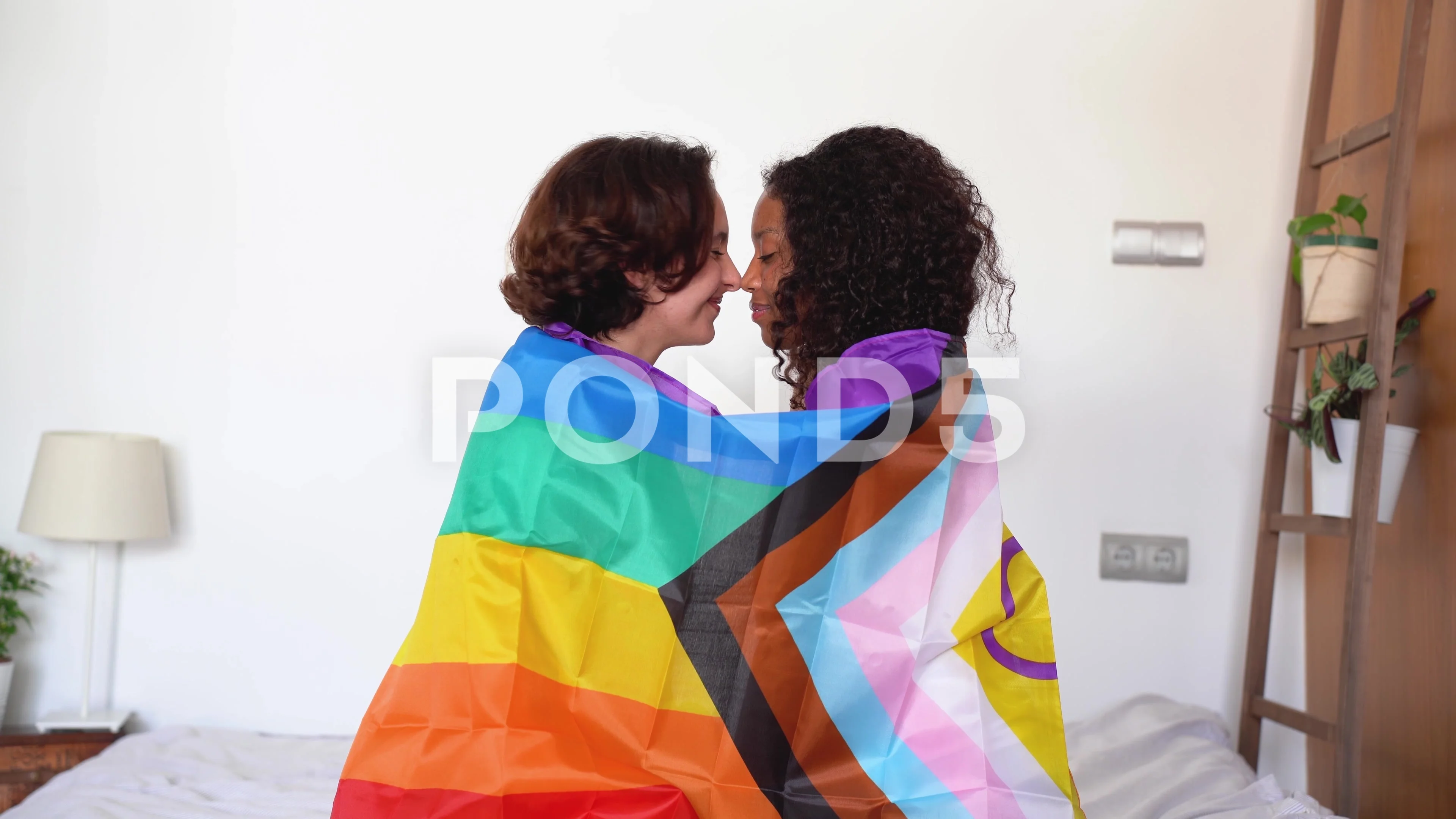 Lesbian couple wrapped in rainbow flag and giving a kiss Stock Photo |  Adobe Stock